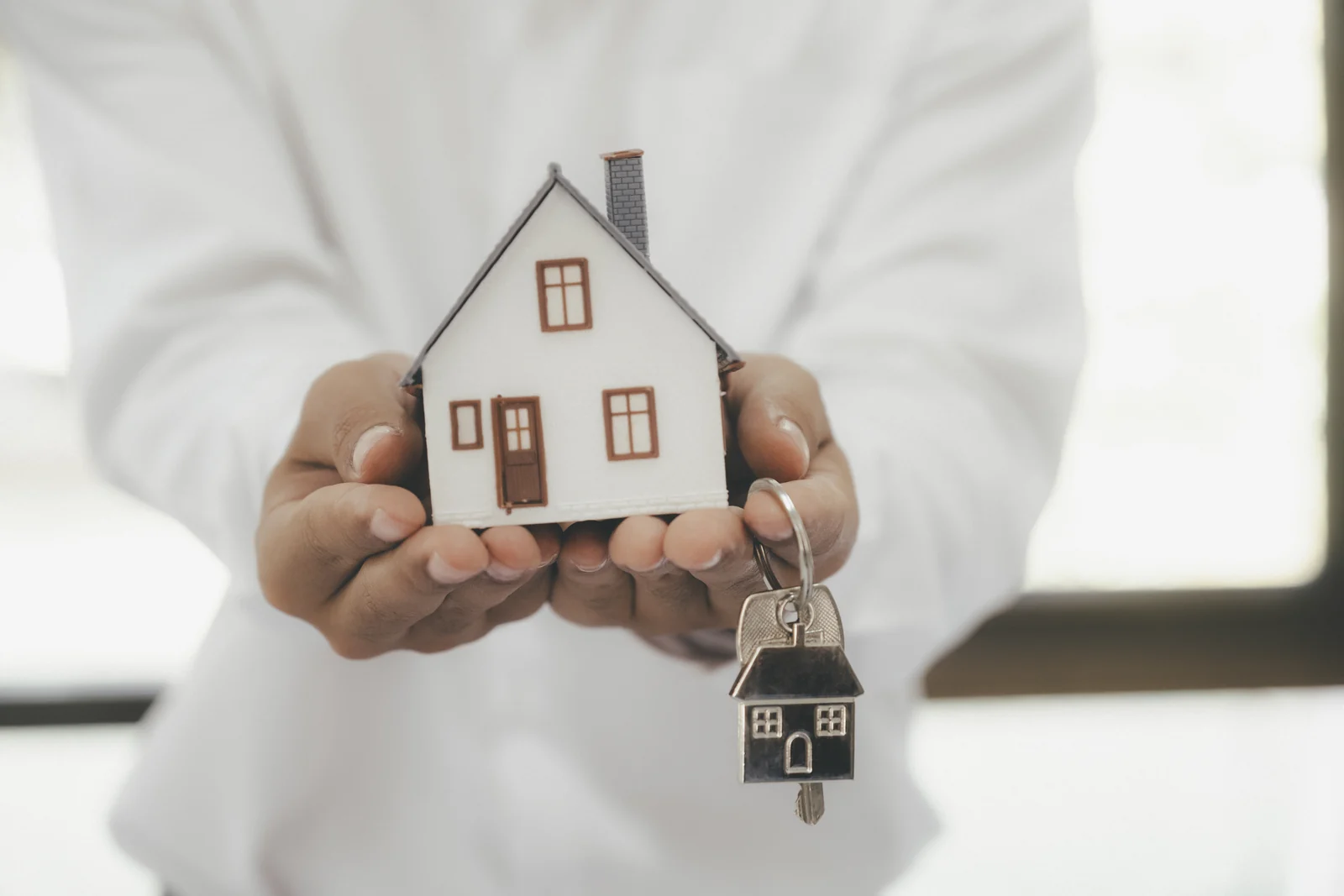 A house and keys held in two hands
